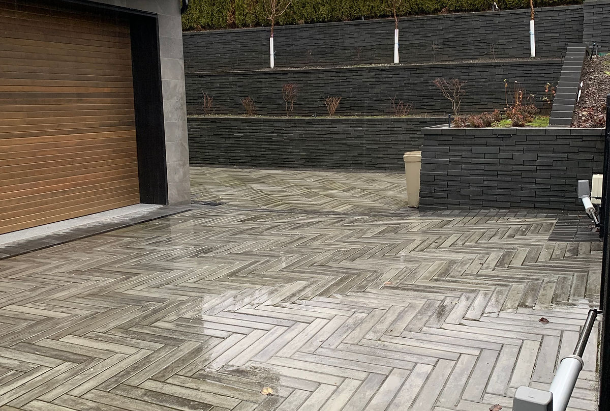 Modern herringbone paver driveway with zen wall by Deerwood Landscaping